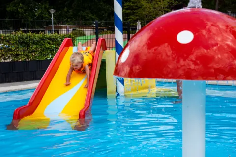 Peuterbad jongen van glijbaan zwembad